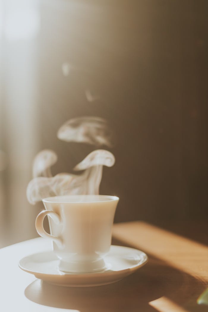 cta-bg Warm steaming cup of coffee on a table with soft morning sunlight.